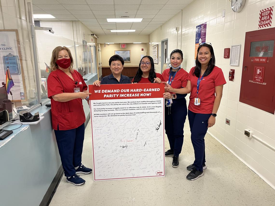 Elmhurst nurses hold a petition board demanding pay parity for NYC Health and Hospitals nurses