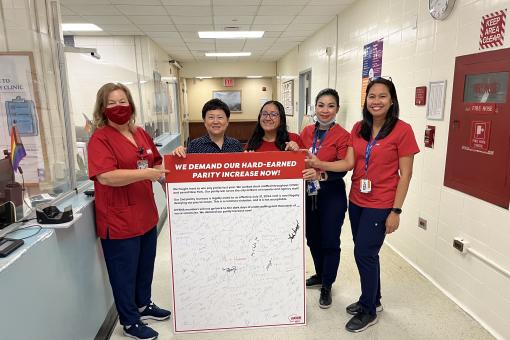 Elmhurst nurses hold a petition board demanding pay parity for NYC Health and Hospitals nurses