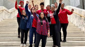 Nurses standing at the stairs in the NY Capitol Building with their fists up