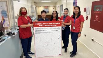 Elmhurst nurses hold a petition board demanding pay parity for NYC Health and Hospitals nurses