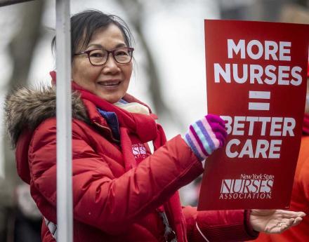 NYSNA member holds up sign that says "More Nurses = Better Care" at the2023 Lunar Year Parade