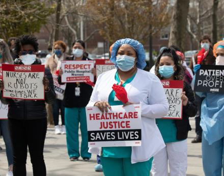 Nurses wearing masks holding signs demanding healthcare justice