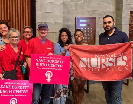 Nurses hold signs saying Save Burdett Birth Center and hold a NYSNA banner